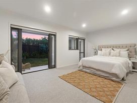 A bedroom featuring a bed, rug, lamp and sofa at Poolside on Moffat - Tauranga