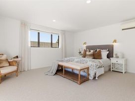 A bedroom with a bed, bedside table, and chair at Poolside on Moffat - Tauranga