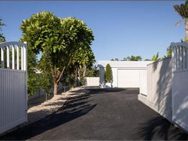 An outdoor area with a gate, driveway, garage, and trees at Poolside on Moffat - Tauranga