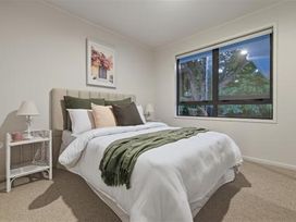 A bedroom with a bed and nightstand at Poolside on Moffat - Tauranga