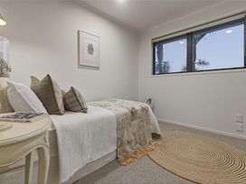 A bedroom with a bed and pillows at Poolside on Moffat - Tauranga