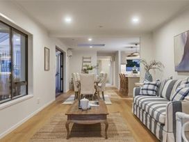 A living room with a sofa and dining table at Poolside on Moffat - Tauranga