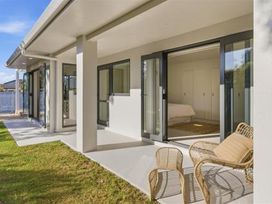 An outdoor patio with chairs and a view of a bedroom at Poolside on Moffat - Tauranga