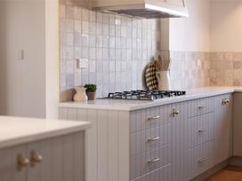A kitchen with cabinets, a gas cooktop, and a plant at Poolside on Moffat - Tauranga