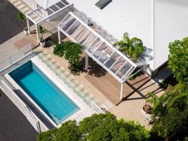 An outdoor area with a swimming pool and glass fencing at Poolside on Moffat - Tauranga
