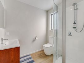 A bathroom with a sink, toilet, shower, and mirror at Sunny Deck Haven - Nelson Holiday Home in Richmond