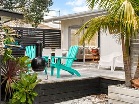 Outdoor deck with chairs and grill at Slice of paradise - Whangamata Holiday Home, Whangamata