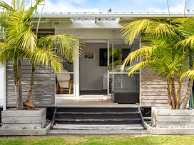 An outdoor area with palm trees and a view of the entrance at Slice of paradise - Whangamata Holiday Home Whangamata