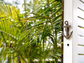An anchor on a white fence with green palm leaves at Slice of paradise - Whangamata Holiday Home, Whangamata