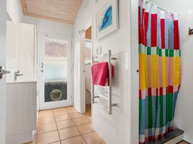 A bathroom with a sink, toilet, and colorful shower curtain at Slice of paradise - Whangamata Holiday Home, Whangamata