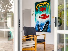 A chair and painting on the wall at Slice of paradise - Whangamata Holiday Home in Whangamata