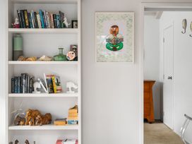 A shelf with books and figurines in a living room at Slice of paradise - Whangamata Holiday Home Whangamata