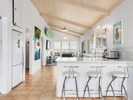 A kitchen with bar stools and a refrigerator at Slice of paradise - Whangamata Holiday Home, Whangamata