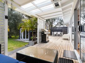 An outdoor living area with a grill and seating at Slice of paradise - Whangamata Holiday Home in Whangamata