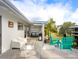 An outdoor deck with chairs and a grill at Slice of paradise - Whangamata Holiday Home, Whangamata