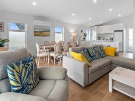 A living room with a sofa and dining area at Pu Corner - Waipu Holiday Home in Waipu