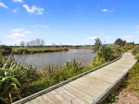A boardwalk by the water with plants and trees at Pu Corner - Waipu Holiday Home Waipu