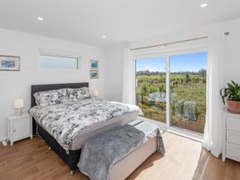 A bedroom with a bed and window overlooking a field at Pu Corner - Waipu Holiday Home, Waipu