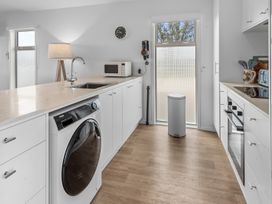 A kitchen with a washing machine and microwave at Pu Corner - Waipu Holiday Home, Waipu