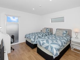A bedroom with two beds and a lamp at Pu Corner - Waipu Holiday Home