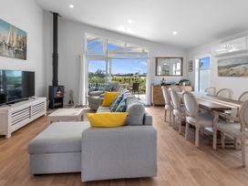 A living room with a sofa and dining area at Pu Corner - Waipu Holiday Home