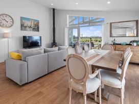 A living room with a sofa, television, and dining table at Pu Corner - Waipu Holiday Home in Waipu