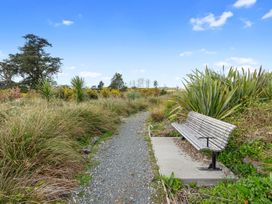 A path with a bench and plants at Pu Corner - Waipu Holiday Home in Waipu