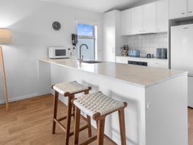 A kitchen with an island and bar stools at Pu Corner - Waipu Holiday Home in Waipu