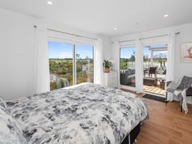 A bedroom with a bed and sliding doors at Pu Corner - Waipu Holiday Home