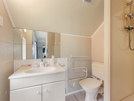 A bathroom with a sink, toilet, shower, and mirror at The Bay house - Moetapu Holiday Home, Moetapu Bay