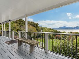 An outdoor area with a bench overlooking the garden and landscape at The Bay house - Moetapu Holiday Home Moetapu Bay