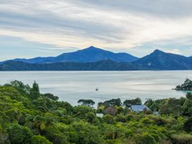 A view of mountains and sea with trees at The Bay house - Moetapu Holiday Home Moetapu Bay