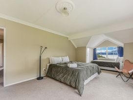 A bedroom with a bed and chair at The Bay house - Moetapu Holiday Home Moetapu Bay