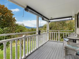 A balcony with chairs and a table at Treetops & Tide Cottage - Moetapu Bay
