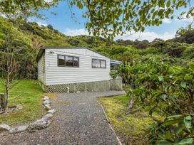 An exterior view of a house surrounded by trees at Treetops & Tide Cottage - Moetapu Holiday Home Moetapu Bay
