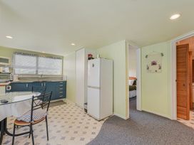 A kitchen with a refrigerator and dining table at Treetops & Tide Cottage - Moetapu Bay
