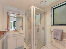 A bathroom with a shower and sink at Treetops & Tide Cottage - Moetapu Bay