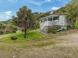 A house with a porch and trees at Treetops & Tide Cottage - Moetapu Holiday Home Moetapu Bay