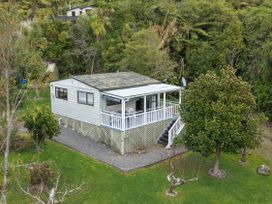 A cottage with a porch and trees at Treetops & Tide Cottage - Moetapu Holiday Home, Moetapu Bay