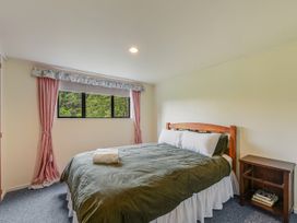 A bedroom with a bed and bedside table at Treetops & Tide Cottage - Moetapu Bay