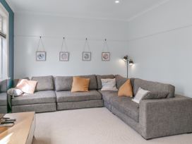A living room with a grey sofa and wall art at Garden Grove - Kapiti Coast Holiday Home, Kapiti Coast