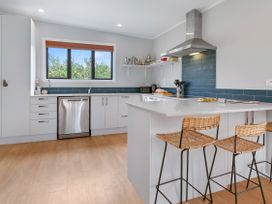 A kitchen with a sink and bar stools at Garden Grove - Kapiti Coast Holiday Home, Kapiti Coast