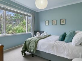 A bedroom with a bed and pillows next to a window at Garden Grove - Kapiti Coast Holiday Home Kapiti Coast