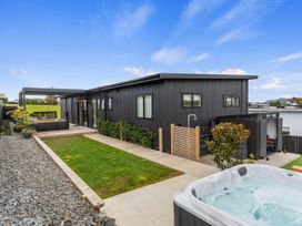 An outdoor area with a hot tub and seating at Langs Life - Waipu Holiday Home Waipu Cove