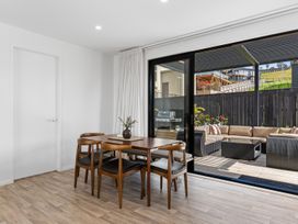 A dining room with a table and chairs looking out to the outdoor seating area at Langs Life - Waipu Holiday Home Waipu Cove
