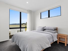 A bedroom with a bed and window at Langs Life - Waipu Holiday Home Waipu Cove