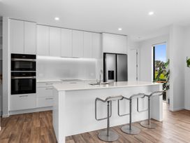 A kitchen with modern appliances and bar stools at Langs Life - Waipu Holiday Home Waipu Cove