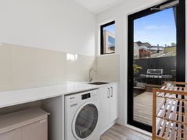 A laundry room with a washing machine and sink at Langs Life - Waipu Holiday Home Waipu Cove