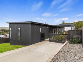 A house with a deck and stone pathway at Langs Life - Waipu Holiday Home Waipu Cove
