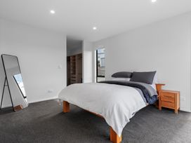 A bedroom with a bed and a mirror at Langs Life - Waipu Holiday Home Waipu Cove